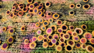 Detalle de un tejido de lana con círculos de colores y espirales.