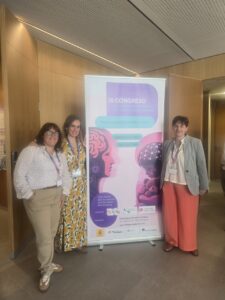 Tres mujeres posan junto al cartel del III Congreso de Trabajo Social Forense.