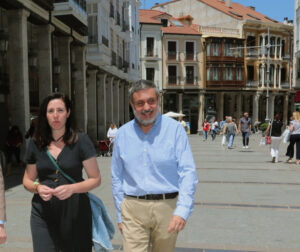 Tres personas caminan por una calle peatonal con edificios y soportales.