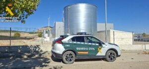 Vehículo de la Guardia Civil estacionado frente a unas instalaciones industriales valladas.