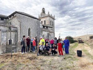 Vecinos reunidos junto a una iglesia durante una actividad de plantación en Villamediana